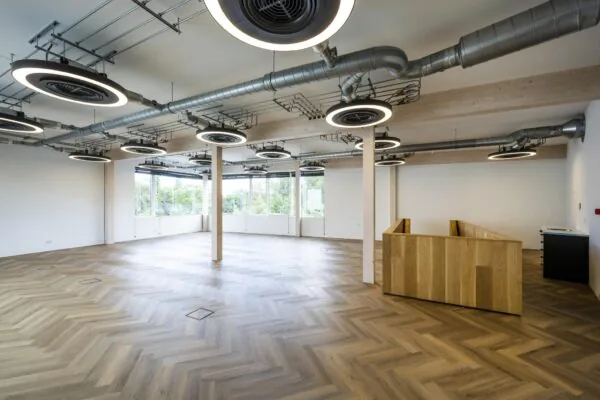 Moderne lege kantoorruimte aan de Fred. Roeskestraat met visgraatvloer, grote ramen en industriële plafondlampen.